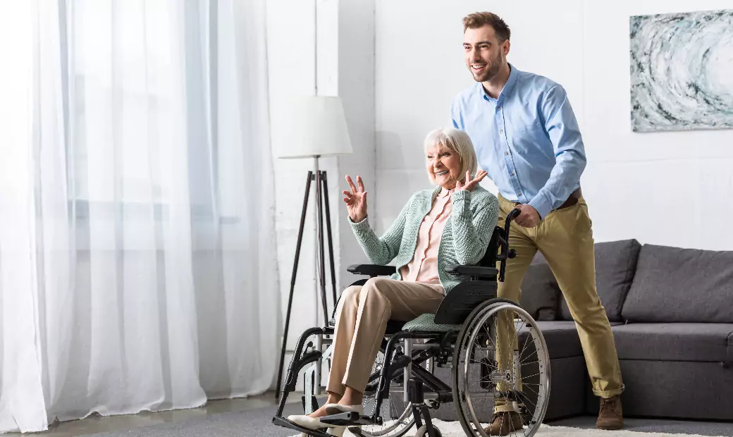 smiling-man-carrying-disabled-senior-mother-on-wheelchair